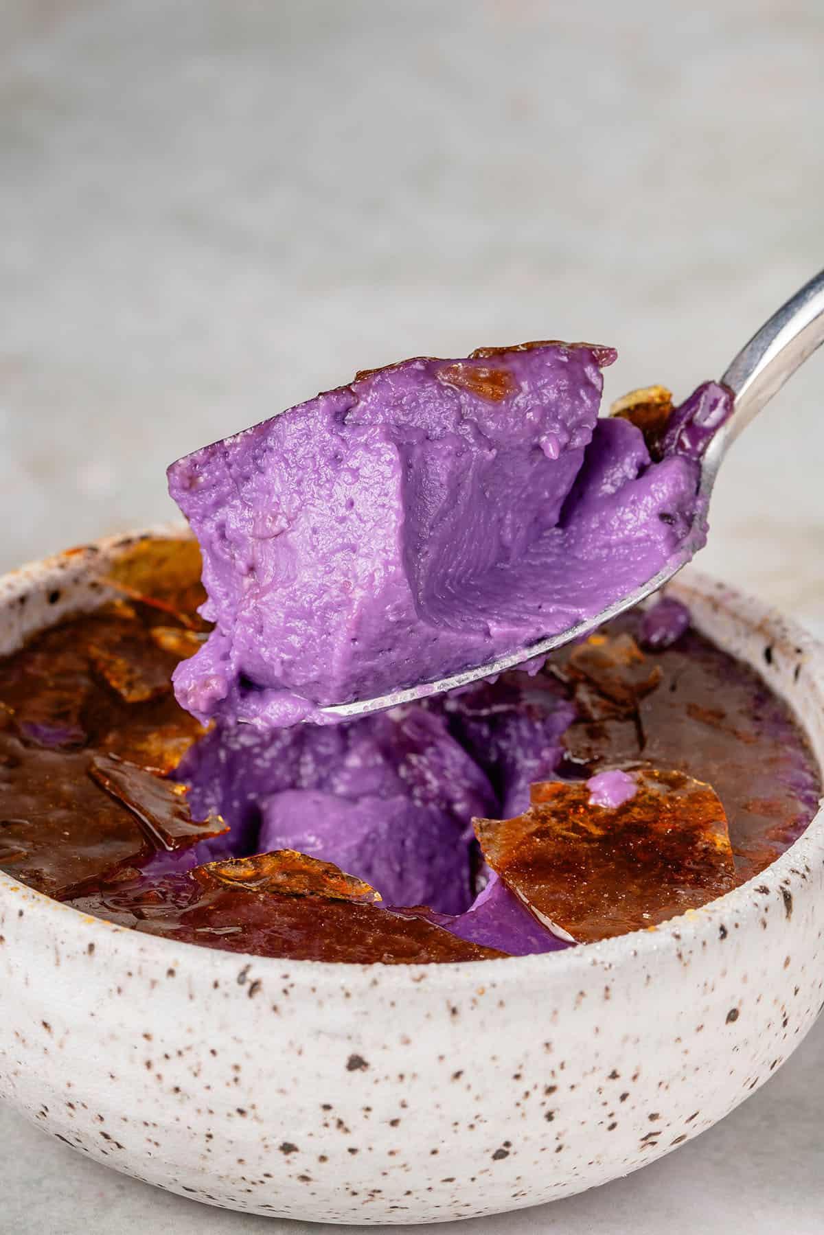 a scoop of Ube Creme Brûlée in a speckled white container