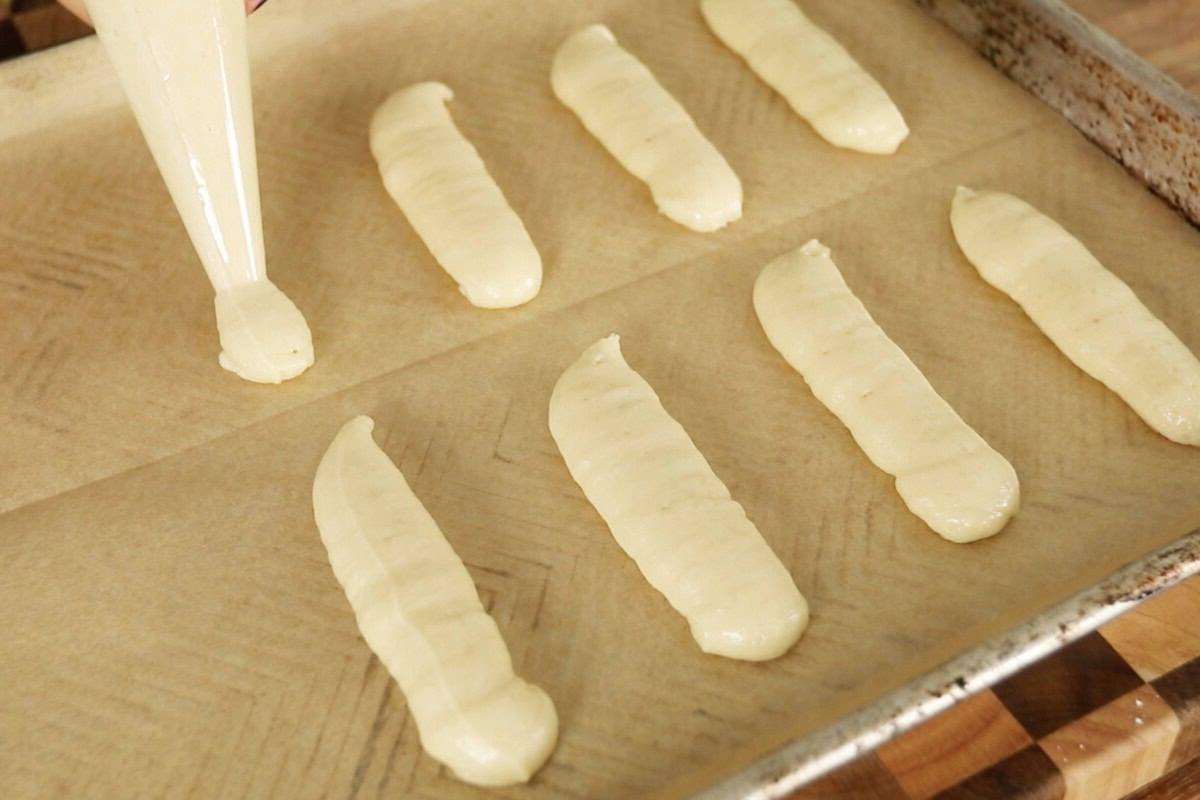 Βήμα-βήμα: Τοποθέτηση ζύμης ladyfinger σε ταψί με λαδόκολλα με σακούλα ζαχαροπλαστικής