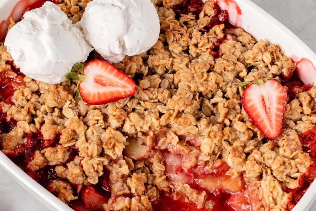 Βέγκαν Κραμπλ Φράουλας και Ραβεντιού 17 horizontal photo of vegan strawberry rhubarb crisp in white baking dish with vanilla ice cream scoops and sliced strawberries