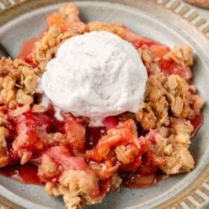 Βέγκαν Κραμπλ Φράουλας και Ραβεντιού 18 close up photo of serving of Vegan Strawberry Rhubarb Crisp on blue plate with scoop of vanilla ice cream