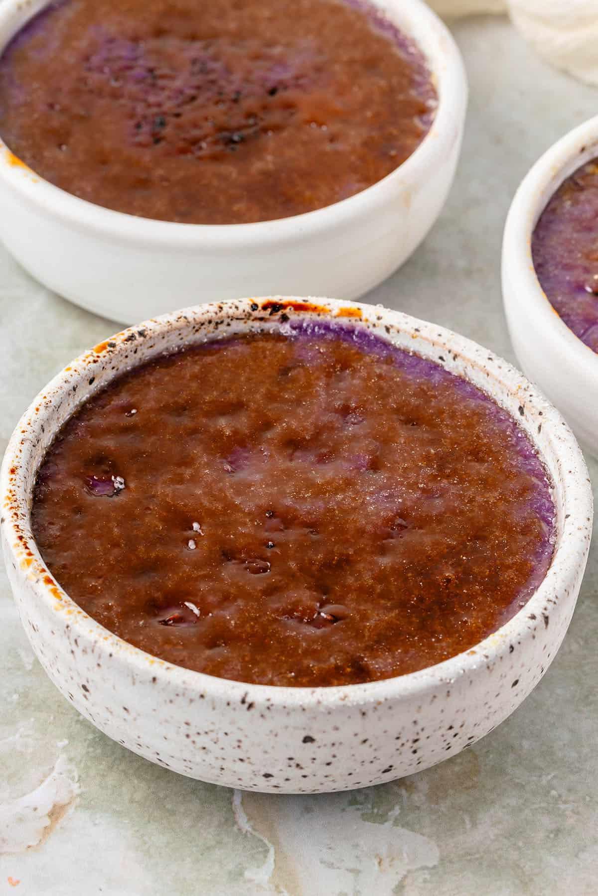 Ube Creme Brûlée in speckled white container covered with caramelized sugar