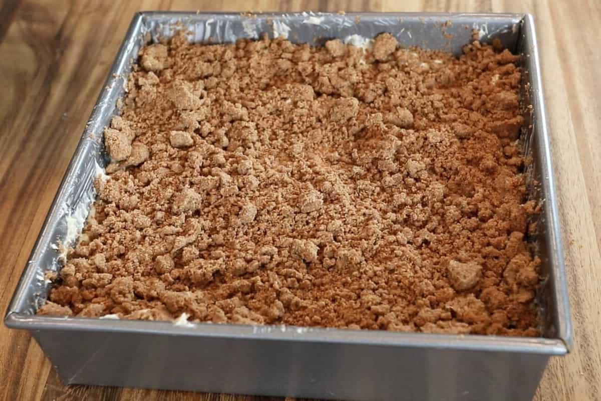 Streusel στρωμένο πάνω από ζύμη κέικ για βίγκαν κέικ καφέ σε ταψί πριν το ψήσιμο