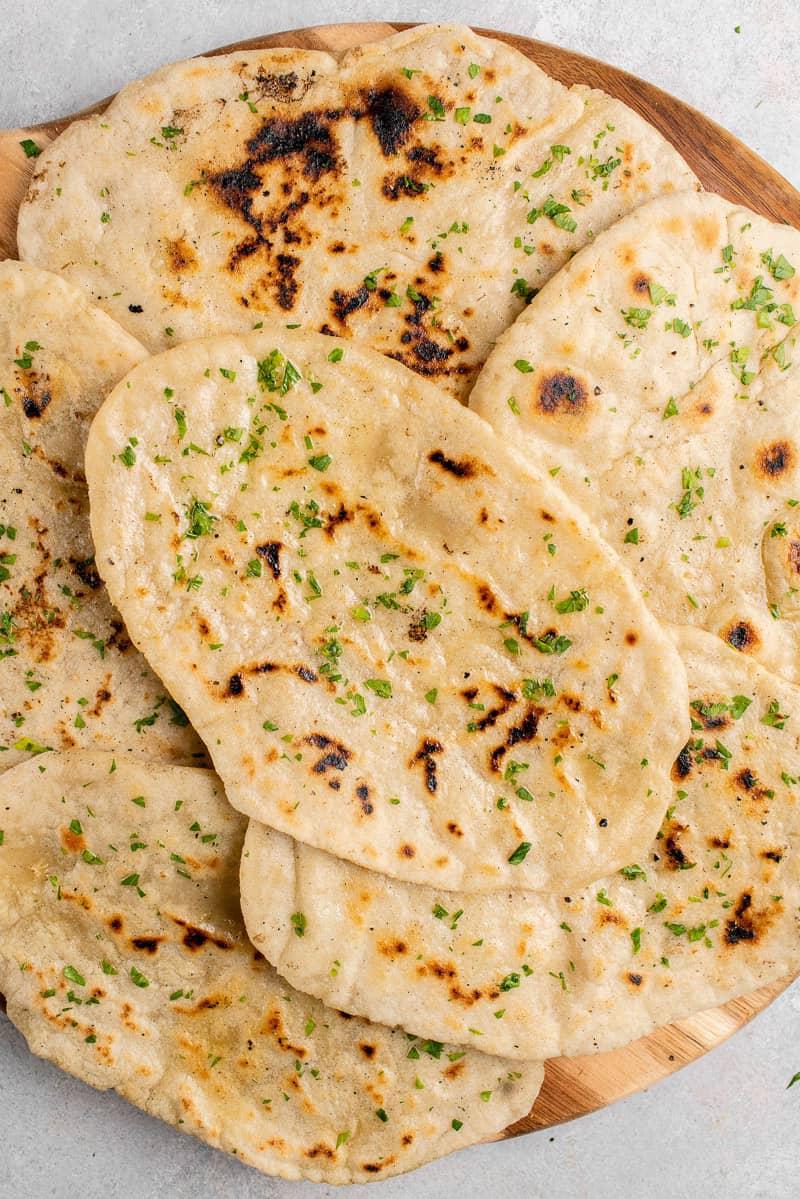 gluten free flatbread with parsley stacked up on a wooden board