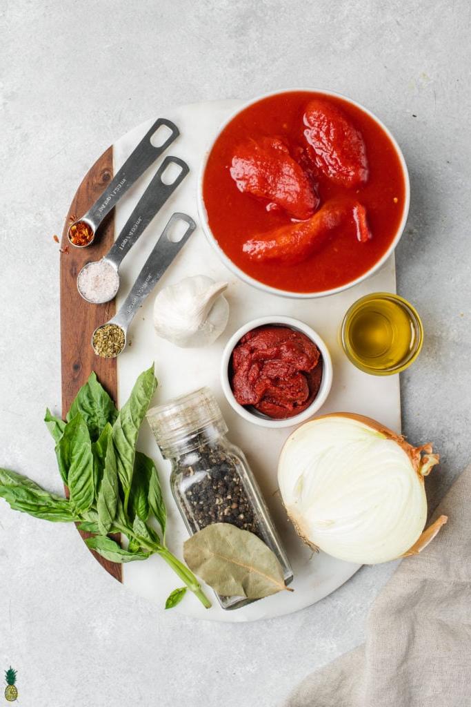 Υλικά για vegan σάλτσα μαρινάρα, ντομάτες, πελτές ντομάτας, κρεμμύδια, βασιλικός, ελαιόλαδο, μπαχαρικά