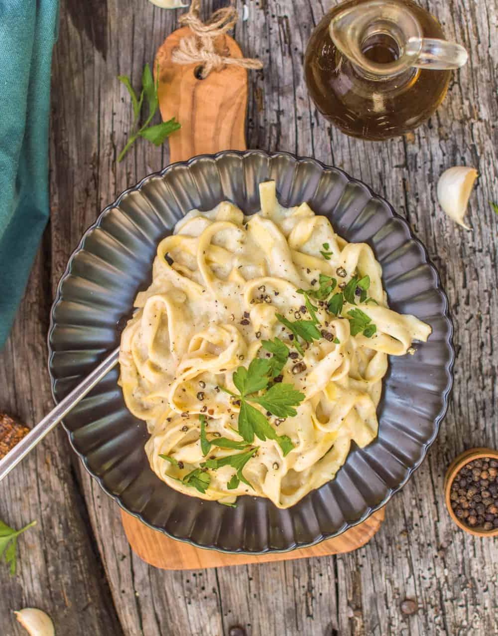 Vegan Φετουτσίνι Αλφρέντο μονοκάτσαρο από πάνω, σε μαύρο πιάτο με πιρούνι.