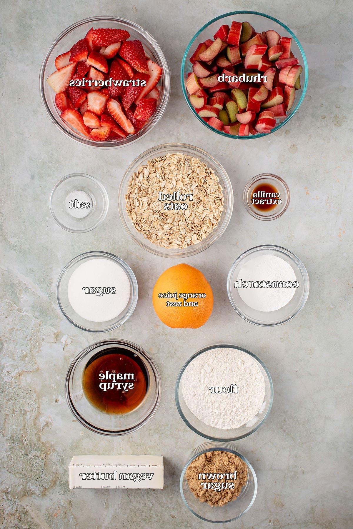 Βέγκαν Κραμπλ Φράουλας και Ραβεντιού 3 labeled ingredients for vegan strawberry rhubarb crisp: rhubarb, strawberries, vanilla extract, rolled oats, salt, cornstarch, orange, sugar, flour, maple syrup, brown sugar and vegan butter