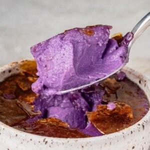 a scoop of Ube Creme Brûlée in a speckled white container