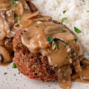 Βίγκαν φιλιππινέζικη μπριζόλα burger σε πιάτο καλυμμένη με σάλτσα μανιταριών και σερβιρισμένη με ρύζι