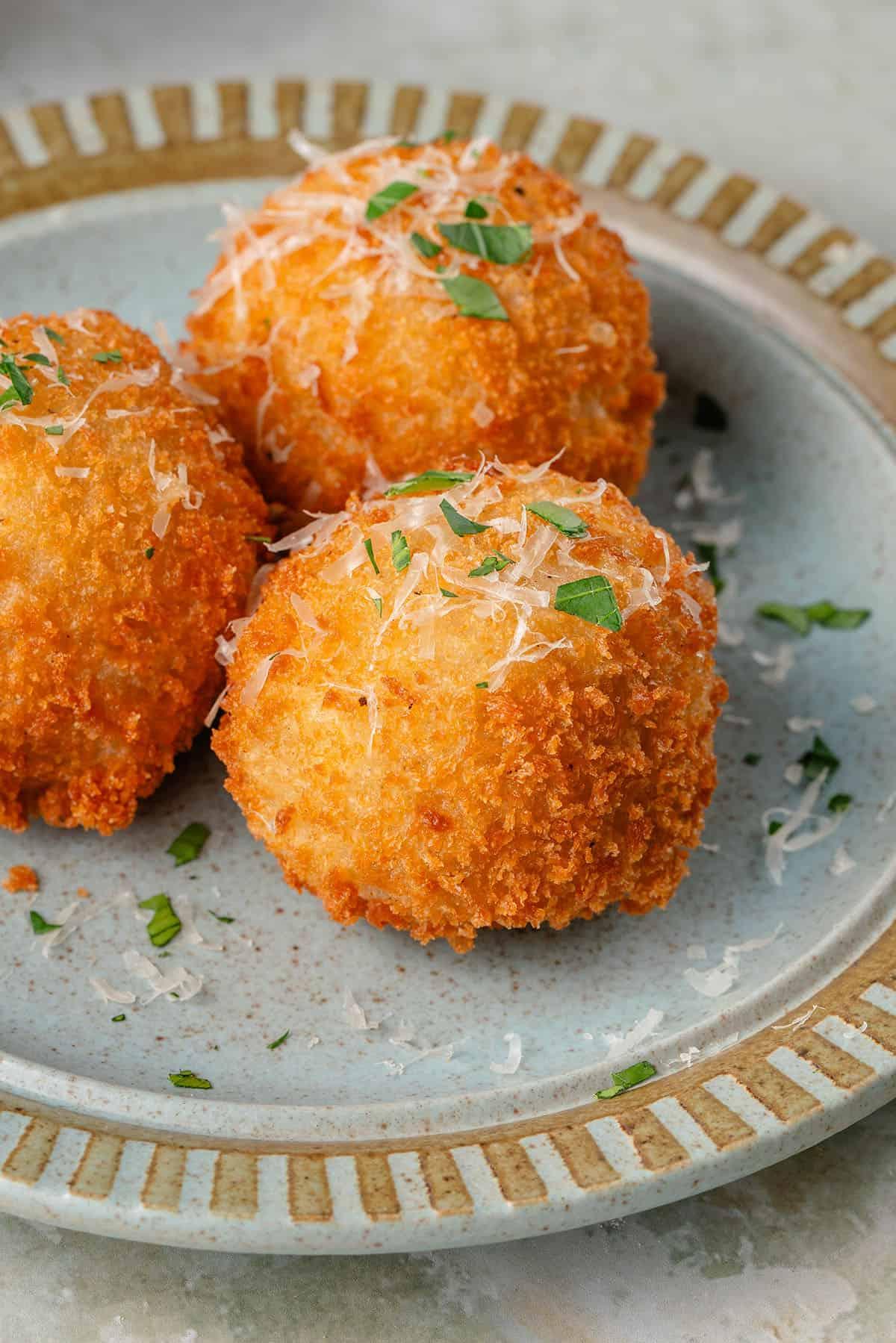 arancini σε μπλε πιάτο με παρμεζάνα και φρέσκο μαϊντανό