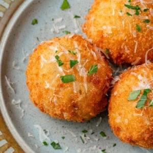 arancini σε μπλε πιάτο με παρμεζάνα και φρέσκο μαϊντανό