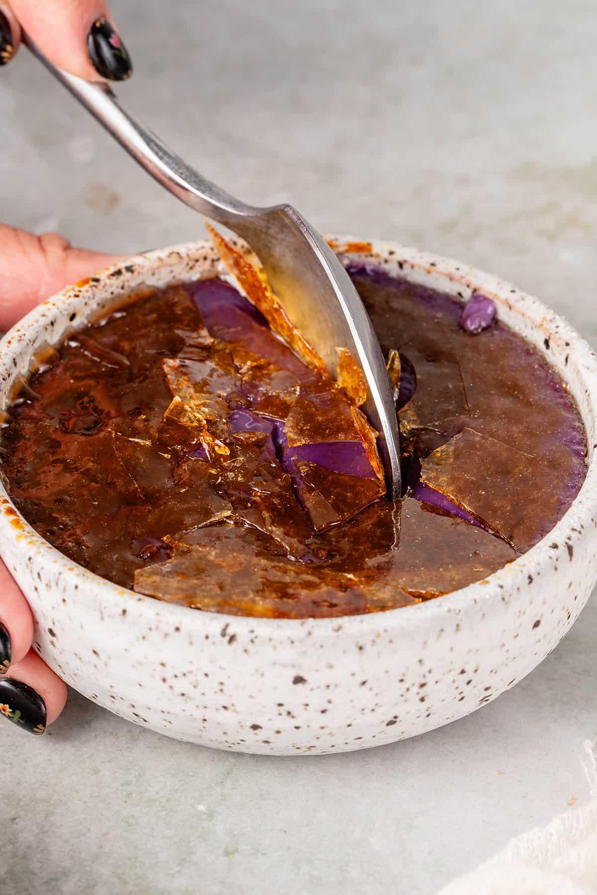 cracking the sugar on the Ube Creme Brûlée with a spoon