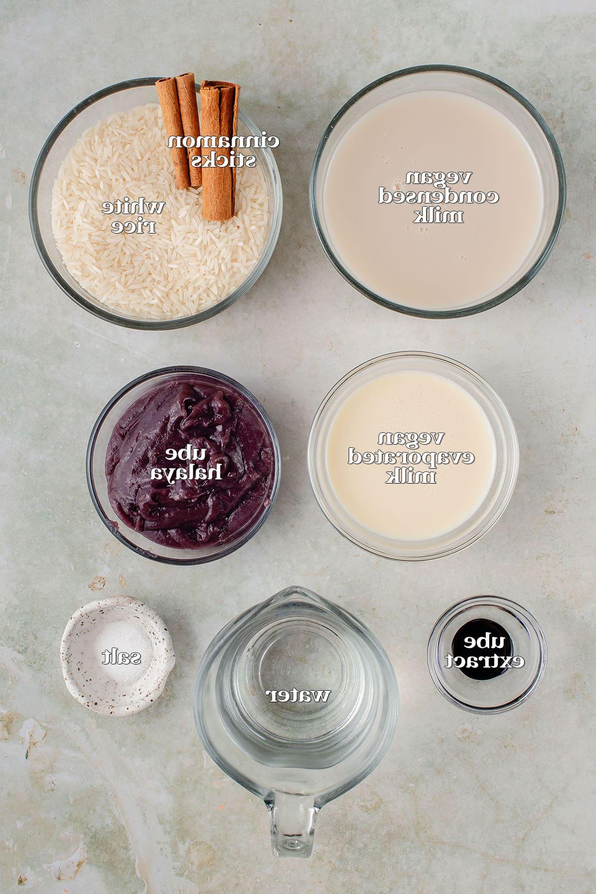 Ούμπε Ορτσάτα (Βίγκαν) 4 labeled ingredients for ube horchata on light green board: vegan condensed milk, cinnamon sticks, white rice, vegan evaporated milk, ube halaya, ube extract, water and salt