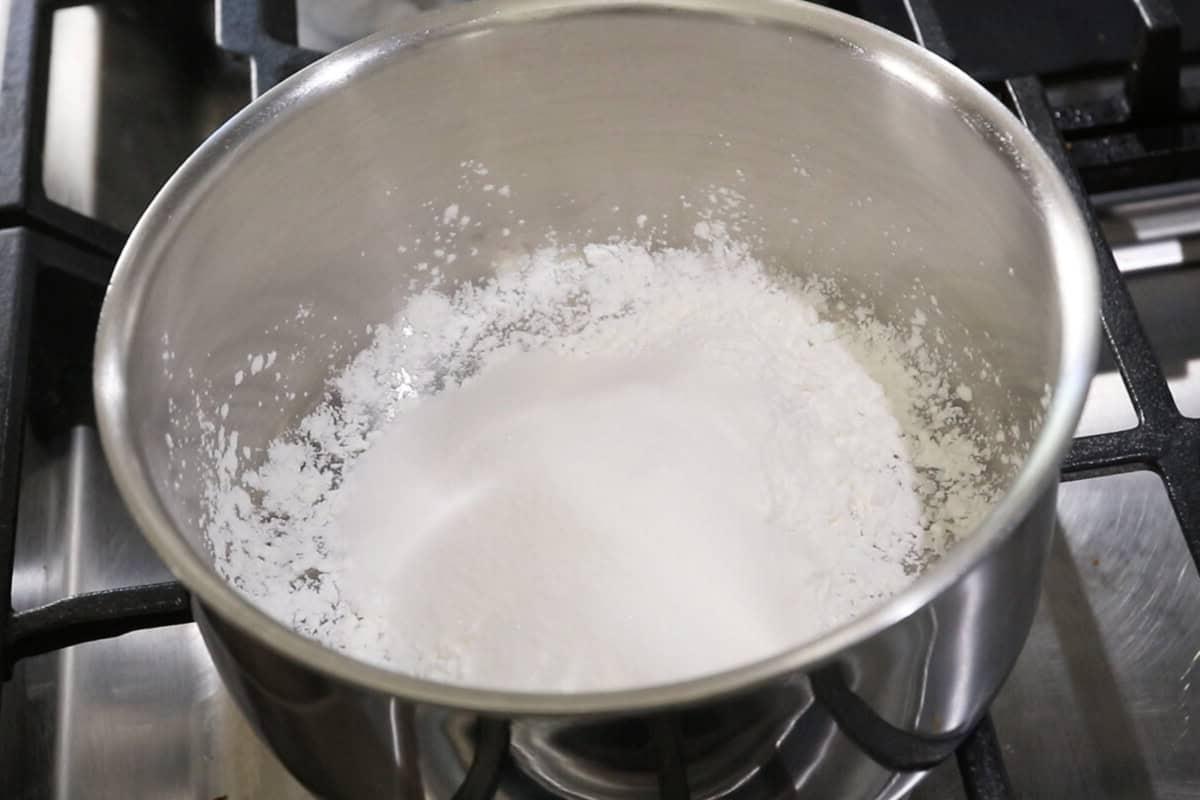 adding sugar to the flour in a pot