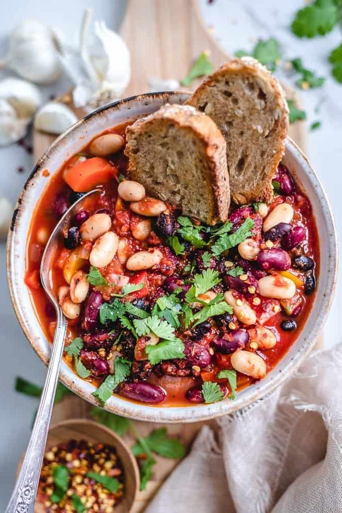 Vegan τσίλι μονοκάτσαρο σε μπολ με ψωμί και κουτάλι.