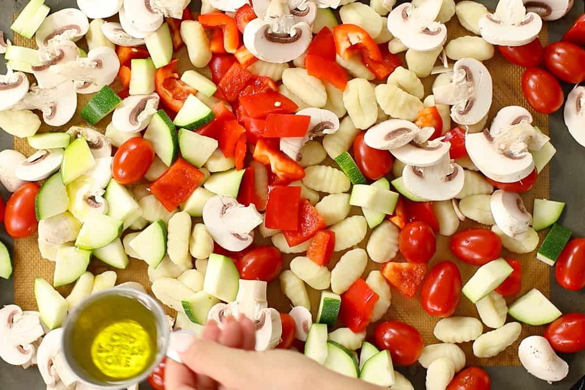ράντισμα ελαιόλαδου σε άψητα νιόκι και λαχανικά σε ταψί