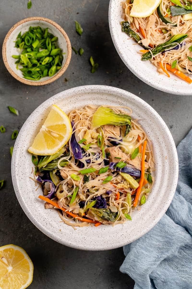 overhead image of bowl of pancit with lemon wedge and green onions on the side