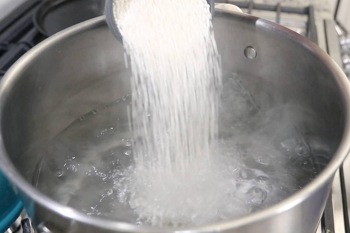 Ρίχνοντας μαργαριτάρια ταπιόκας σε ασημένια κατσαρόλα με βραστό νερό
