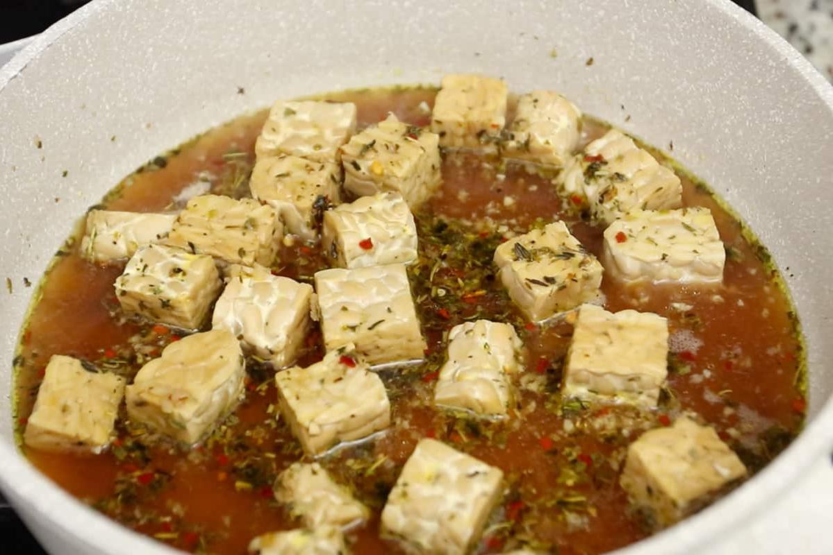 Μαγειρεύοντας τέμπε σε λευκό κεραμικό τηγάνι