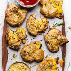 Crispy garlic and herb smashed potatoes with ketchup and vegan parmesan