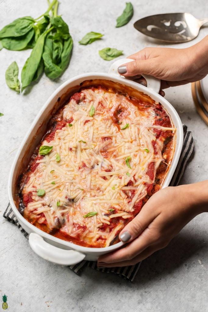 overhead image of eggplant rollatini in baking dish being placed onto table