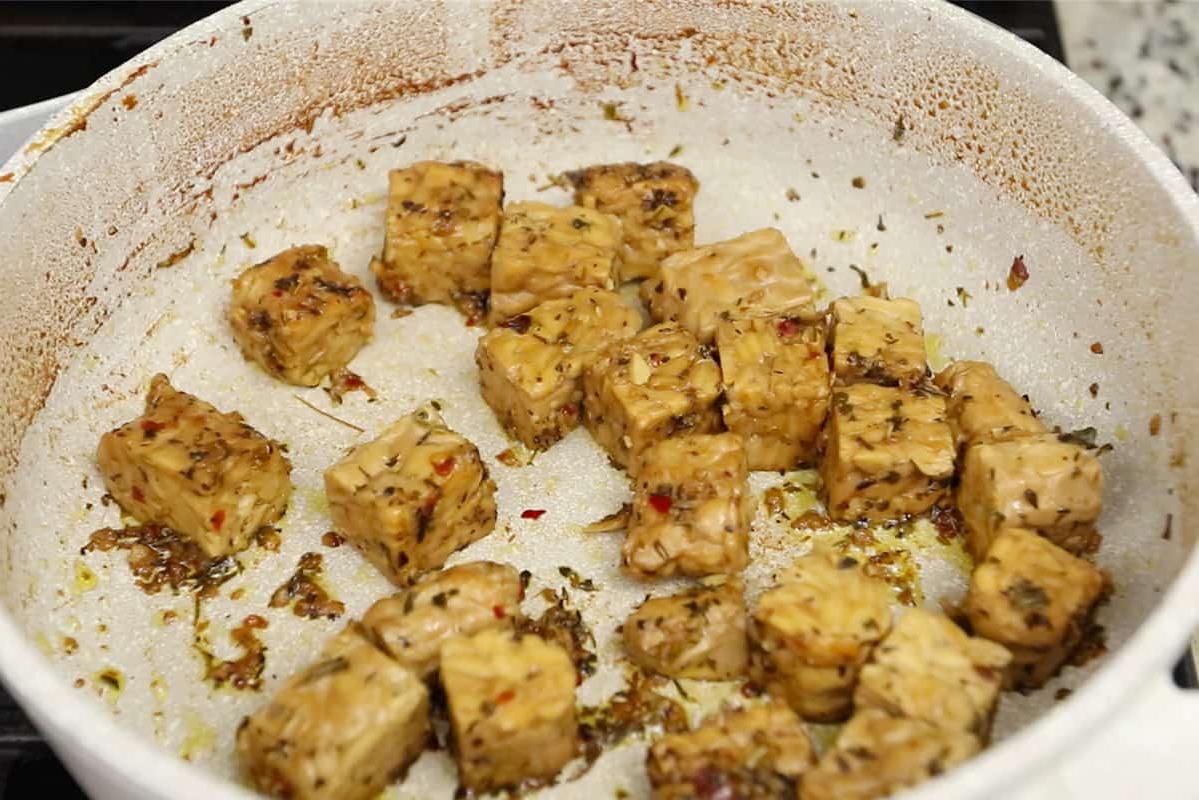 Μαγειρεύοντας τέμπε σε λευκό κεραμικό τηγάνι