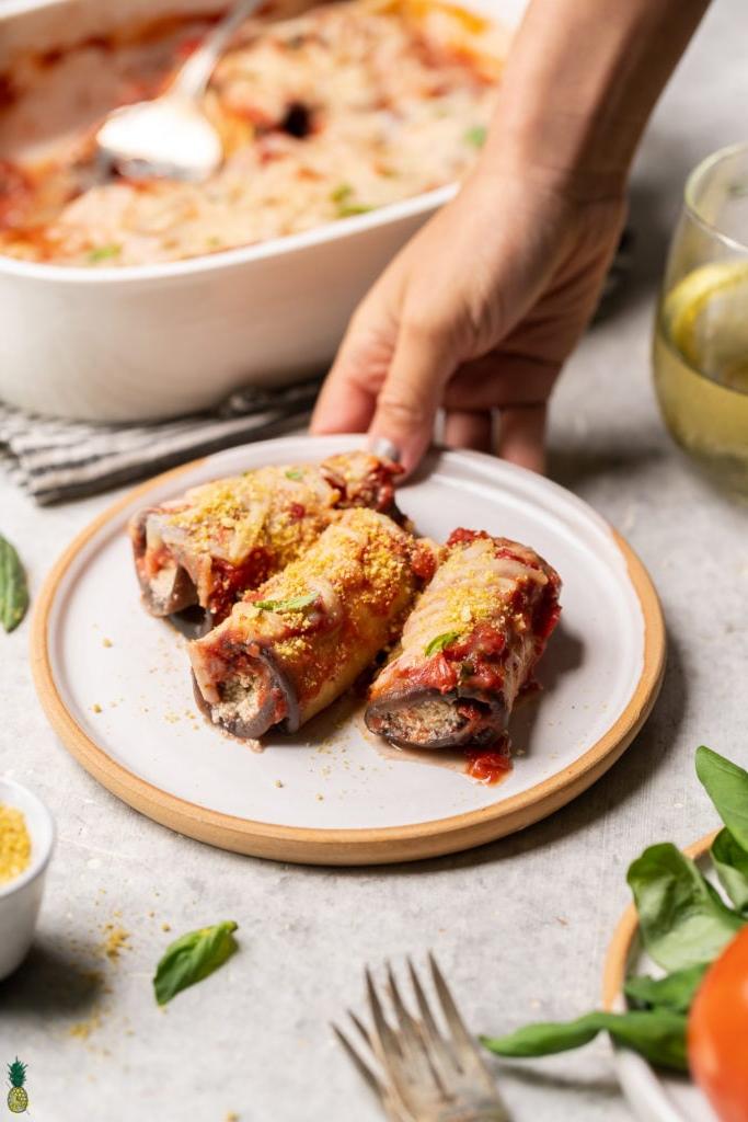 Plate with three eggplant rollatini being held