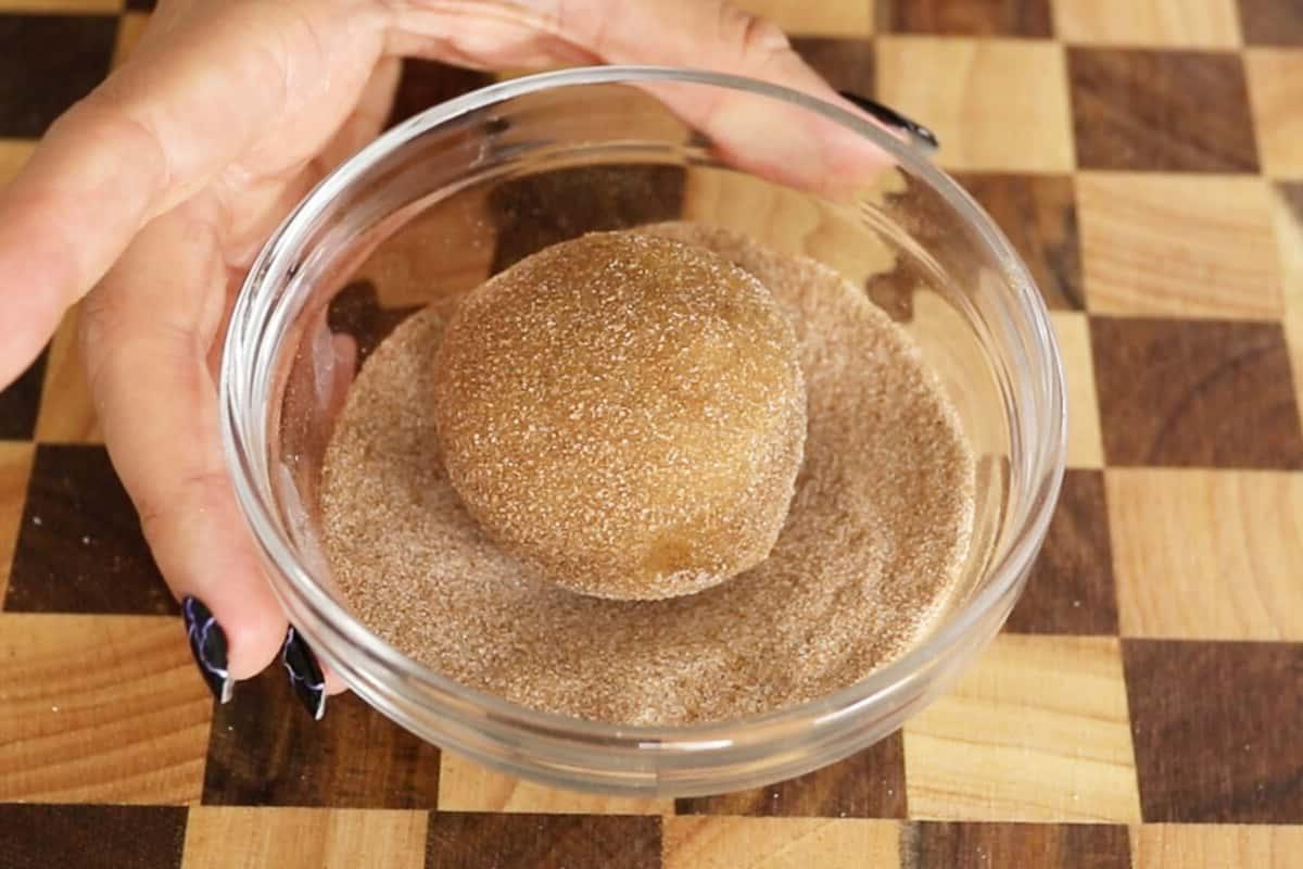rolling vegan pumpkin sugar cookies in granulated sugar