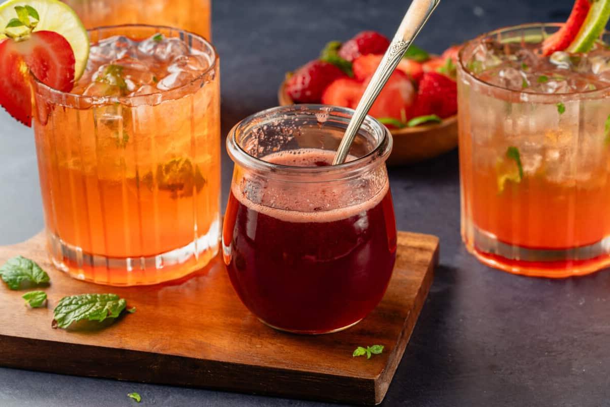 Strawberry Mojito Mocktail και σιρόπι φράουλας σε ξύλινη σανίδα και μπλε τραπέζι