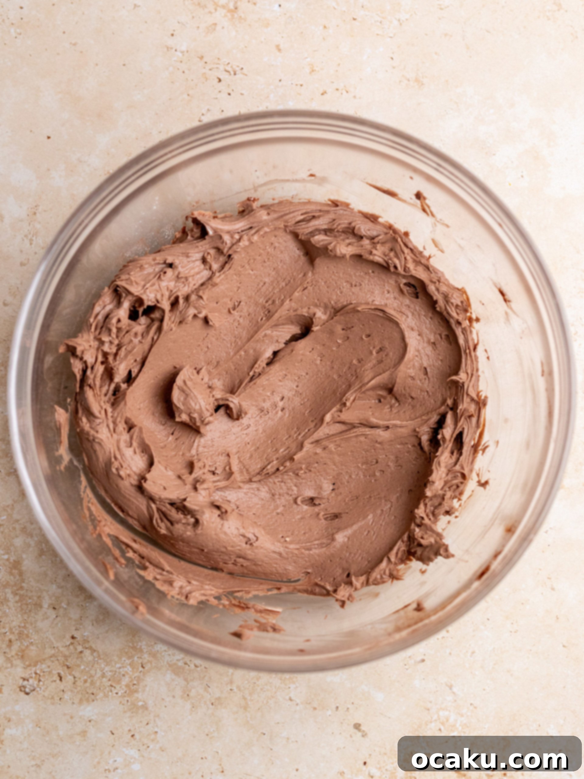 Chocolate ganache being added to the mascarpone mixture in a mixing bowl.