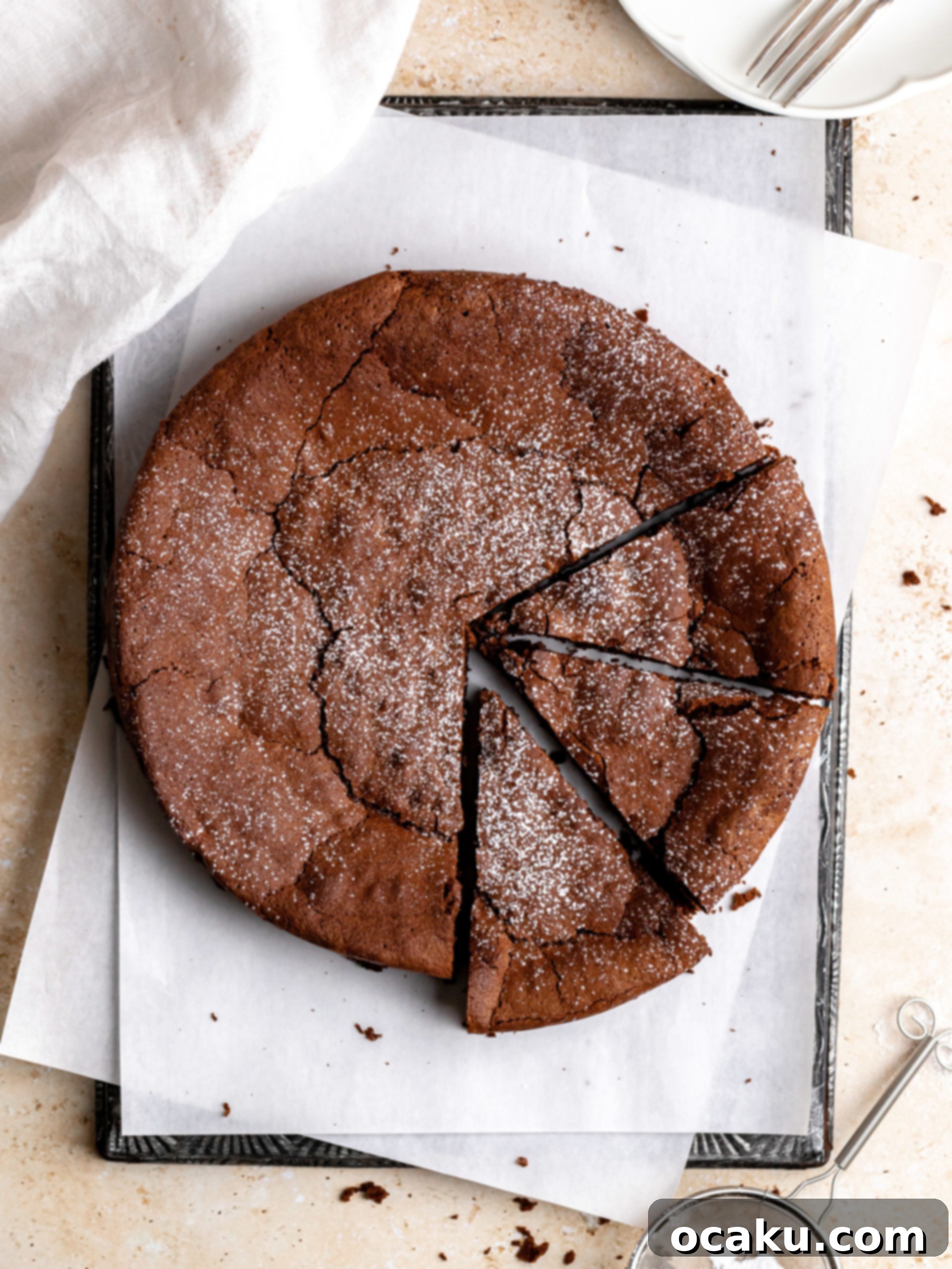 A slice of Flourless Chocolate Espresso Cake on a plate, dusted with powdered sugar and a dollop of whipped cream, with a fork ready to dig in.