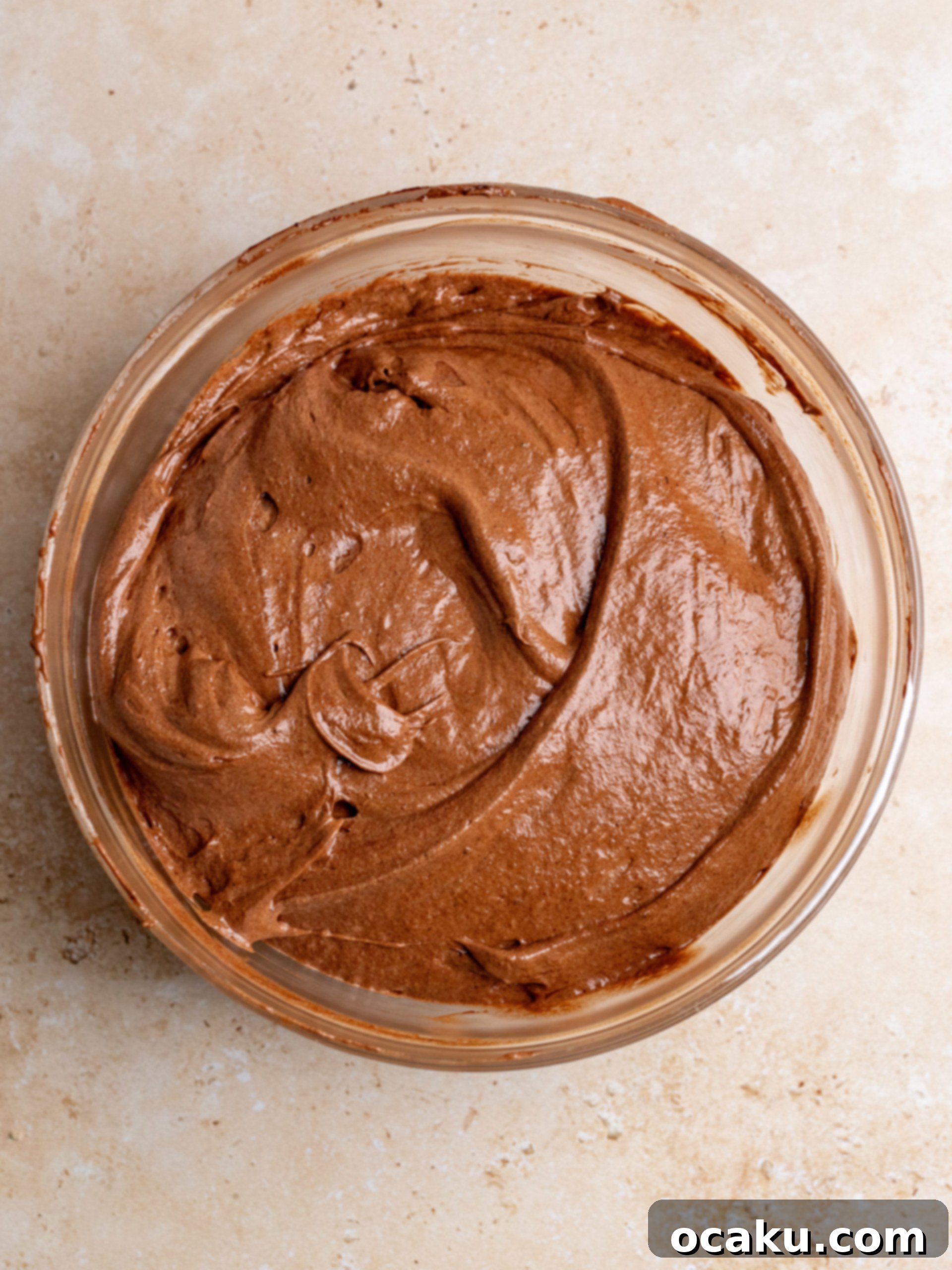 Chocolate espresso cake batter being gently folded with meringue using a rubber spatula.
