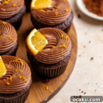 Beautifully frosted chocolate orange cupcake with orange zest and a small orange slice on top.