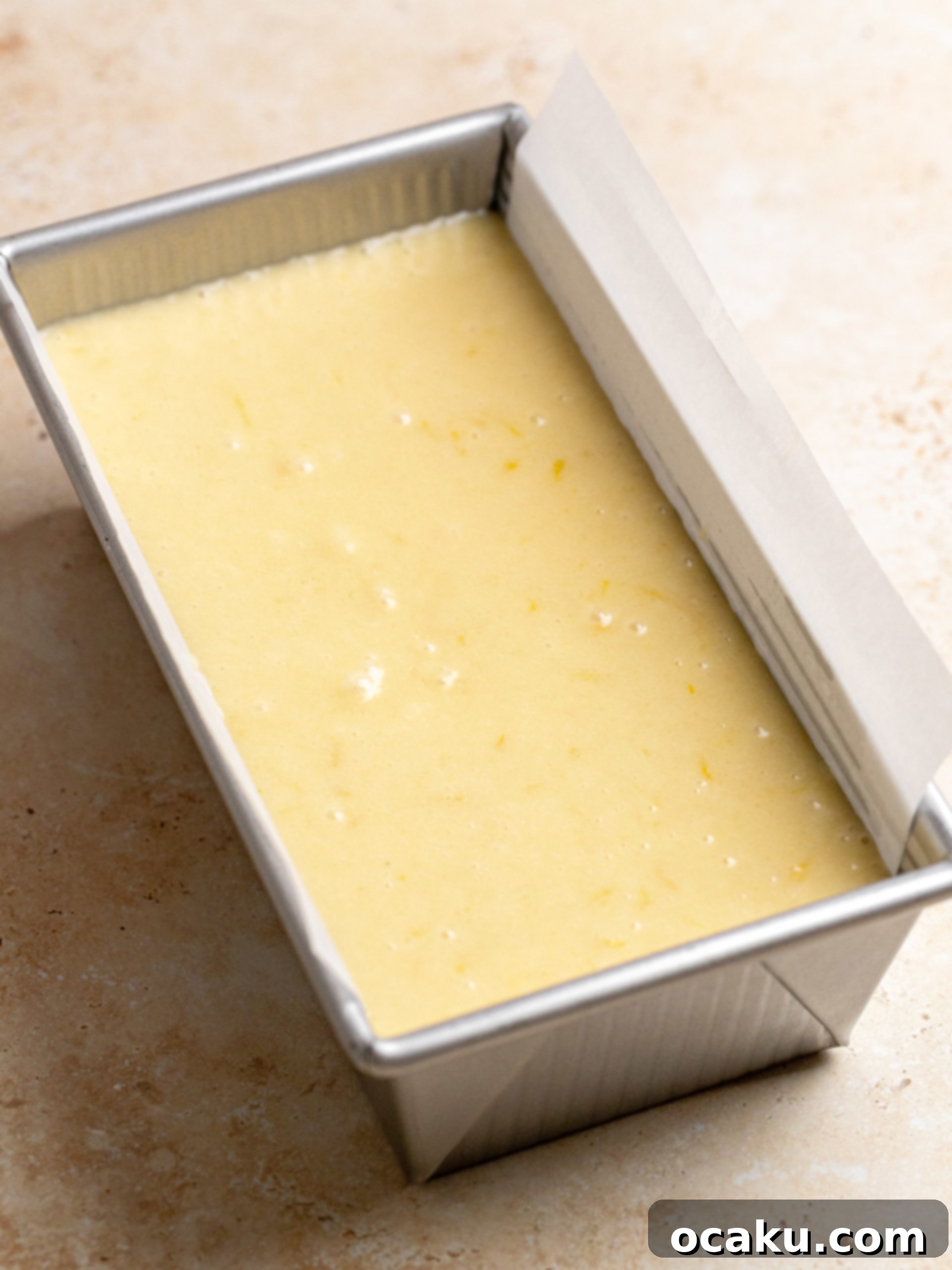 A golden-brown lemon loaf cake cooling in its pan on a wire rack.