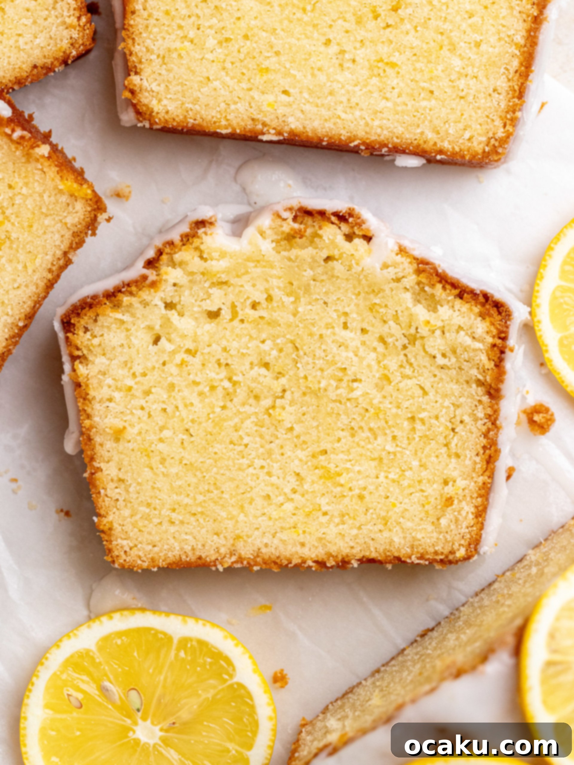 A whole lemon loaf cake, glazed and decorated with lemon slices, ready to be served.