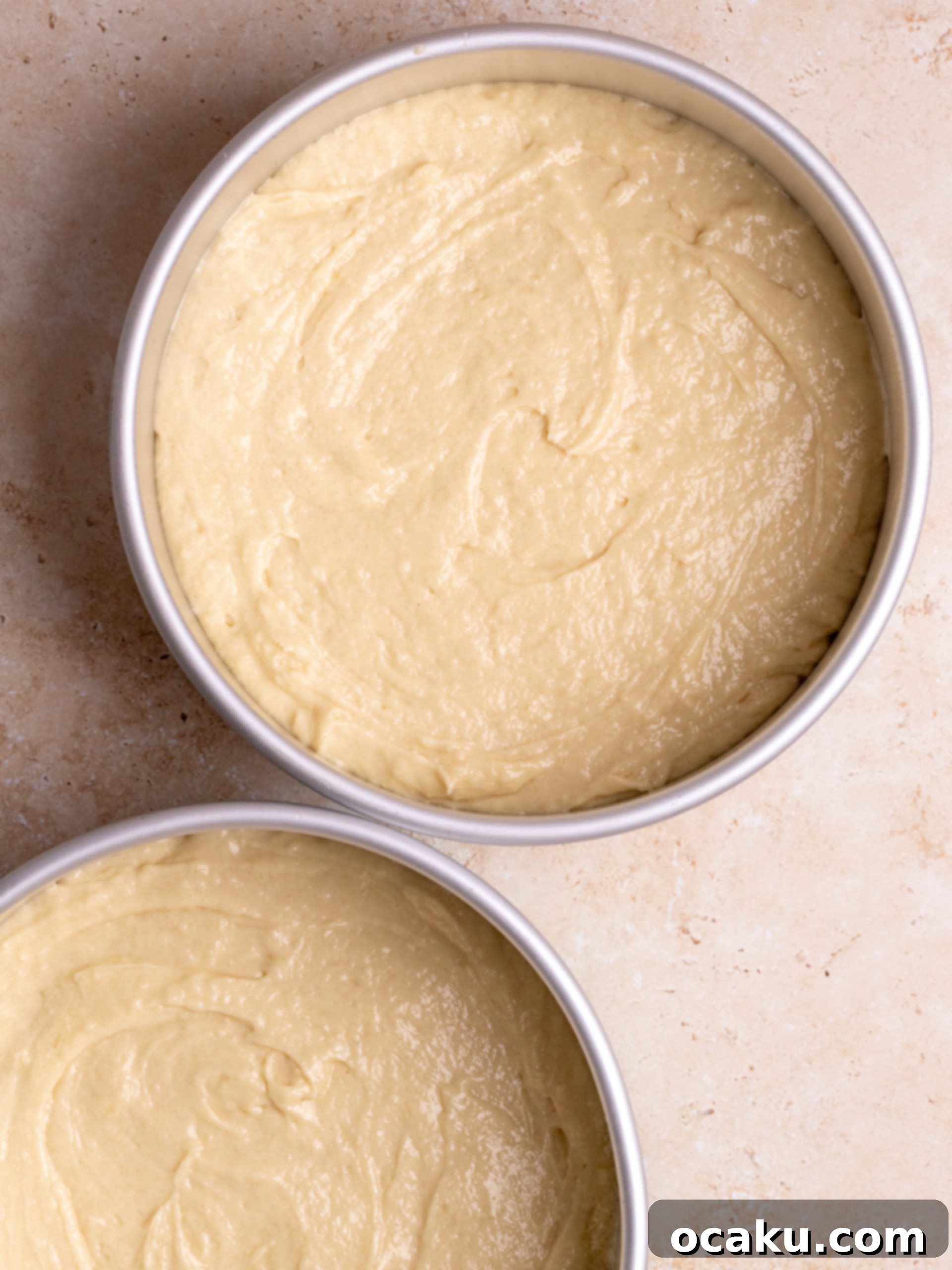 Vanilla cake batter being poured into a baking pan.