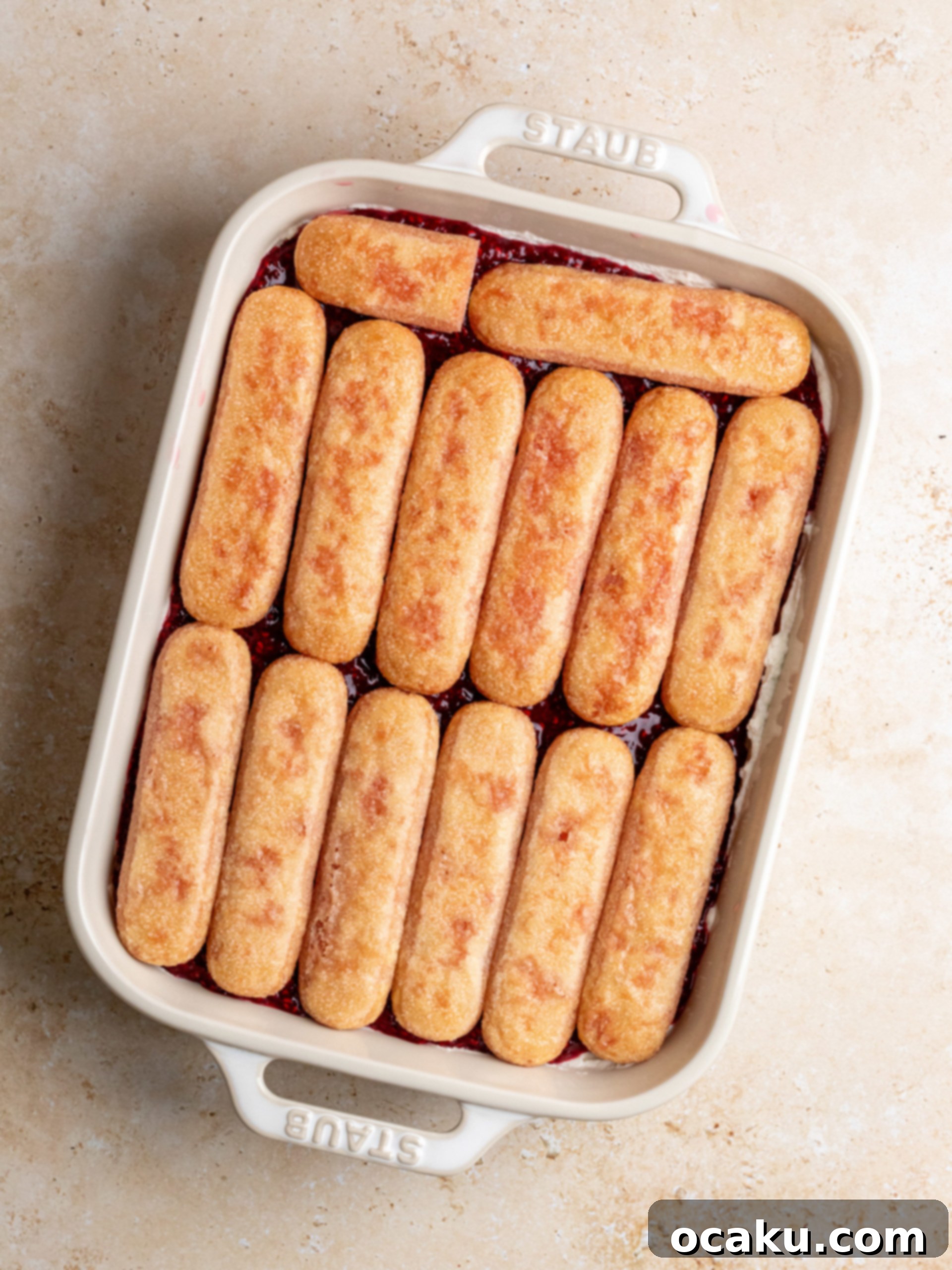 Raspberry Dream Tiramisu 9 Layering ladyfinger cookies dipped in raspberry syrup in a baking dish over a base of mascarpone cream.