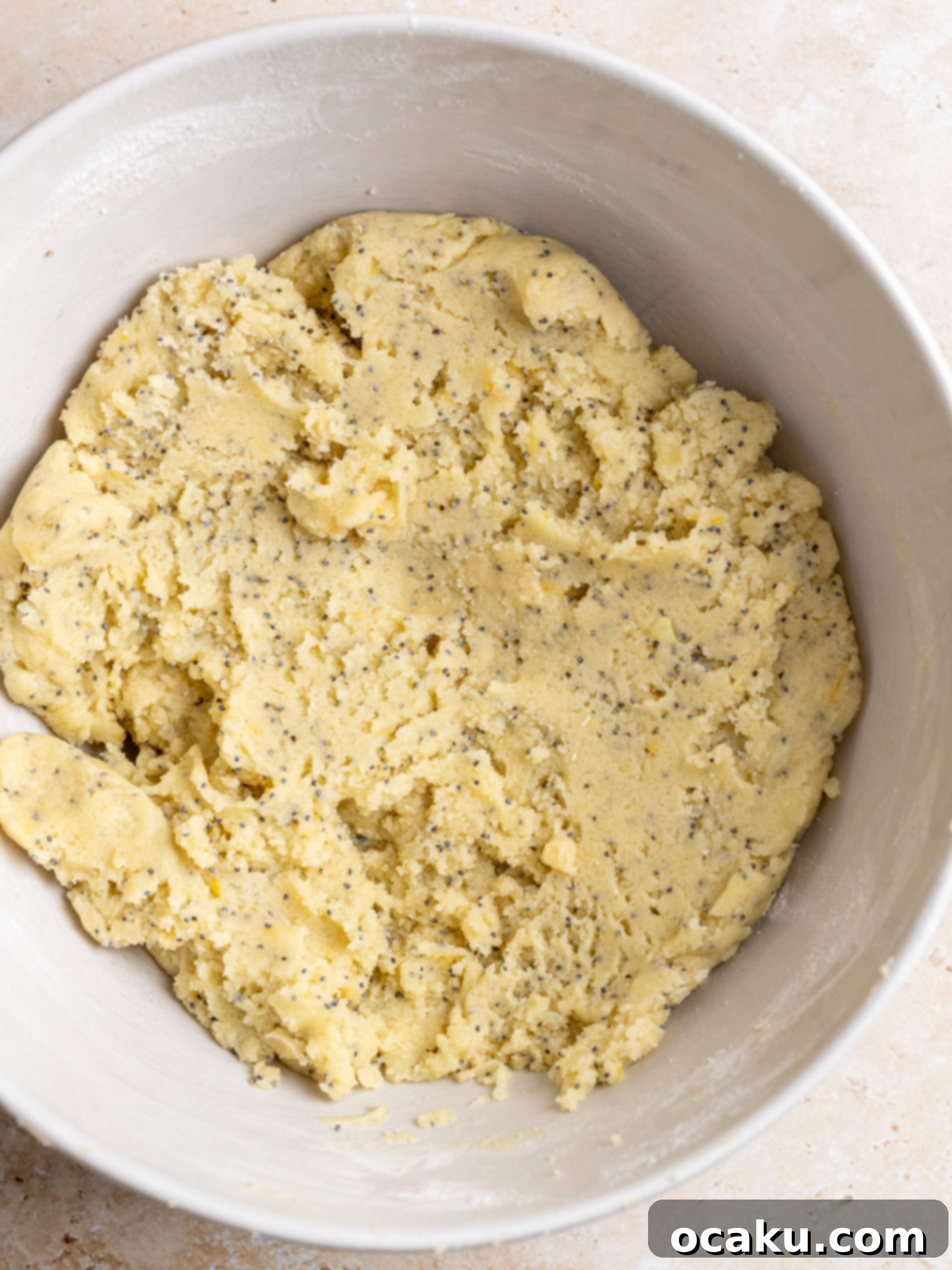 Lemon zest being rubbed into granulated sugar in a mixing bowl