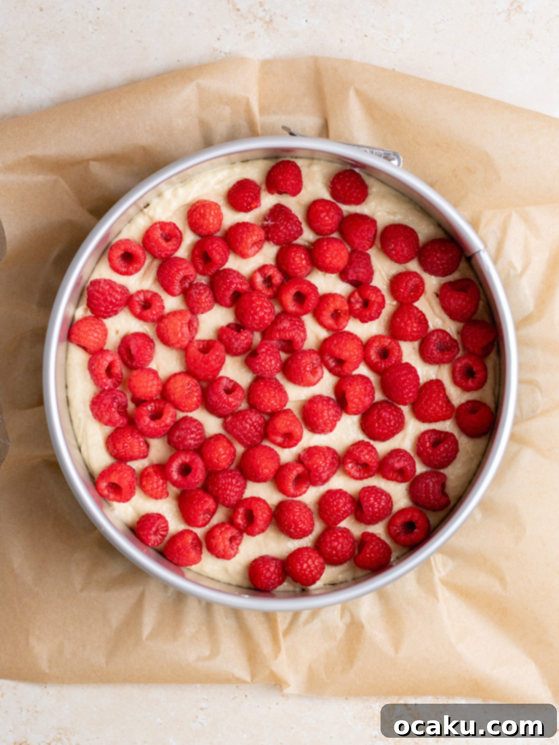 Cake batter with fresh raspberries and sliced almond flakes perfectly arranged before baking