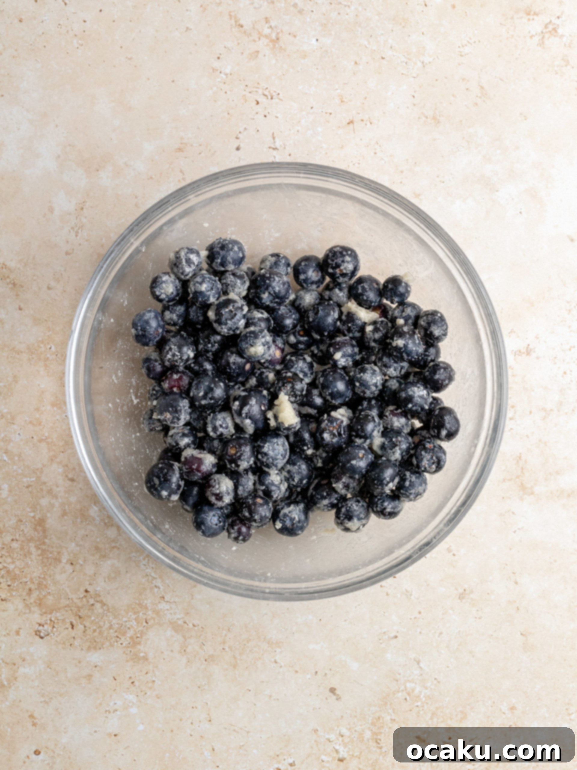 Melted butter being added to the blended cookie crumbs in a food processor.