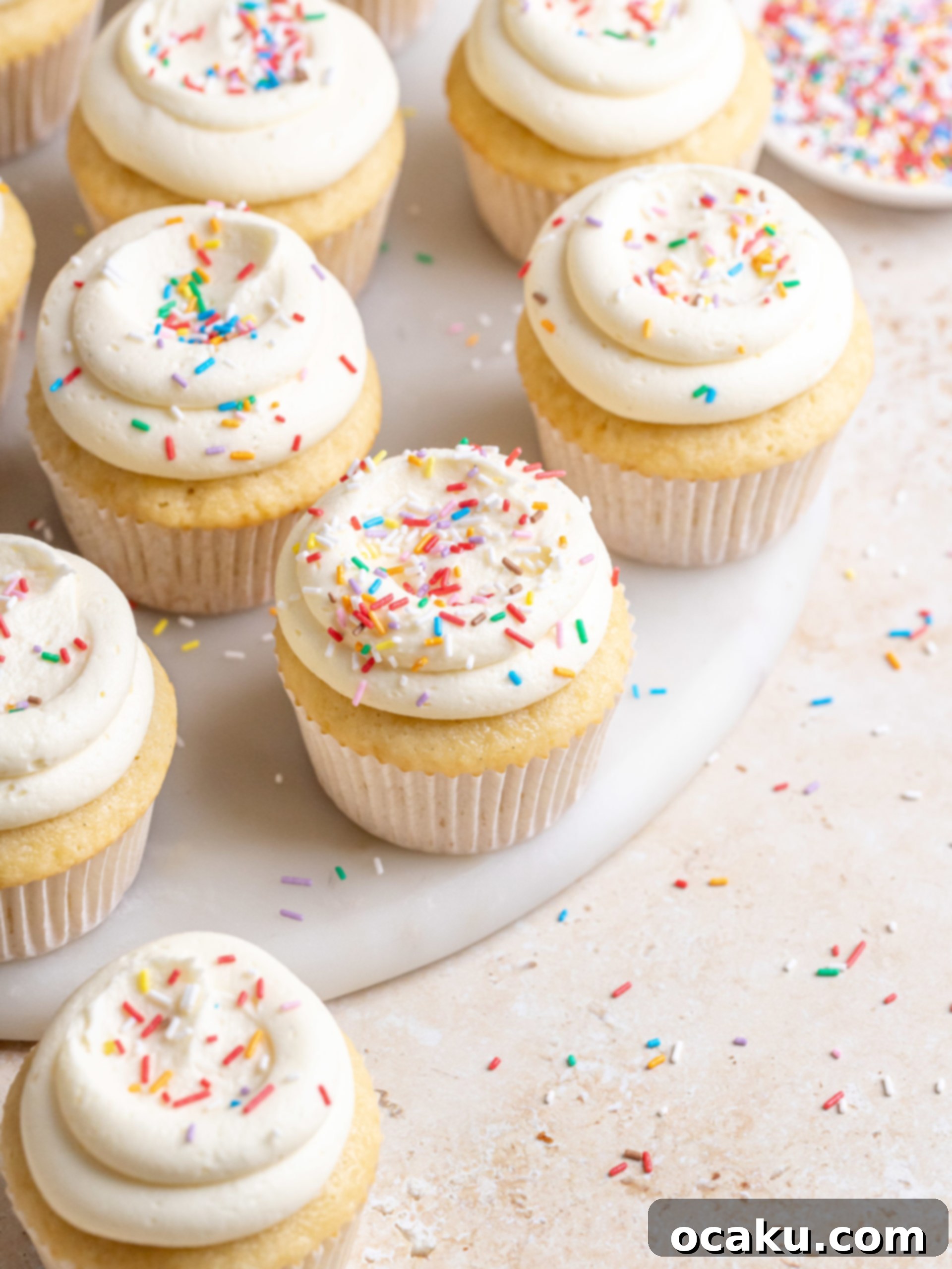Two perfectly frosted vanilla birthday cupcakes adorned with colorful sprinkles, showcasing the smooth buttercream.