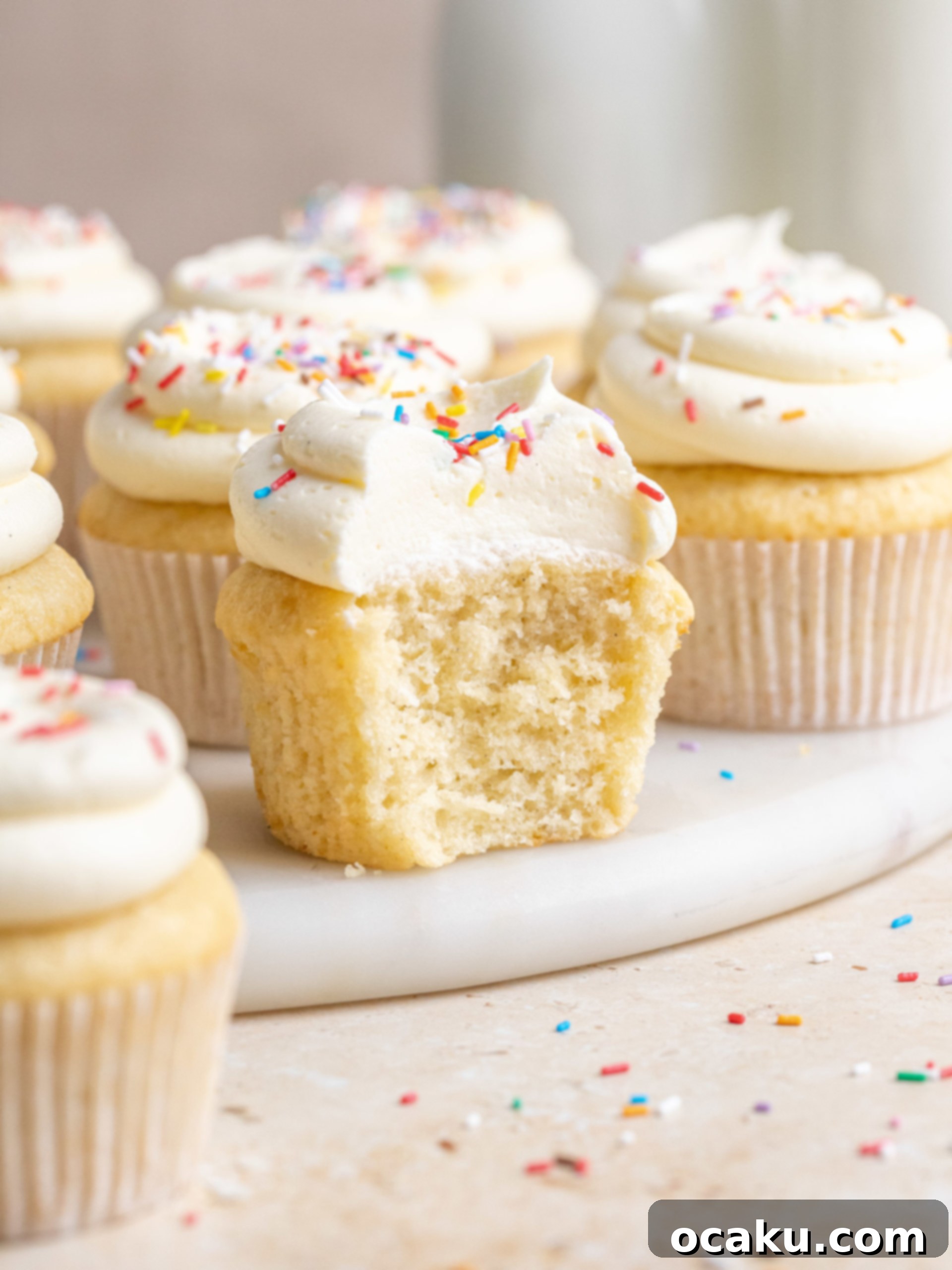 A platter of perfectly frosted and decorated vanilla birthday cupcakes, ready to be served at a party.