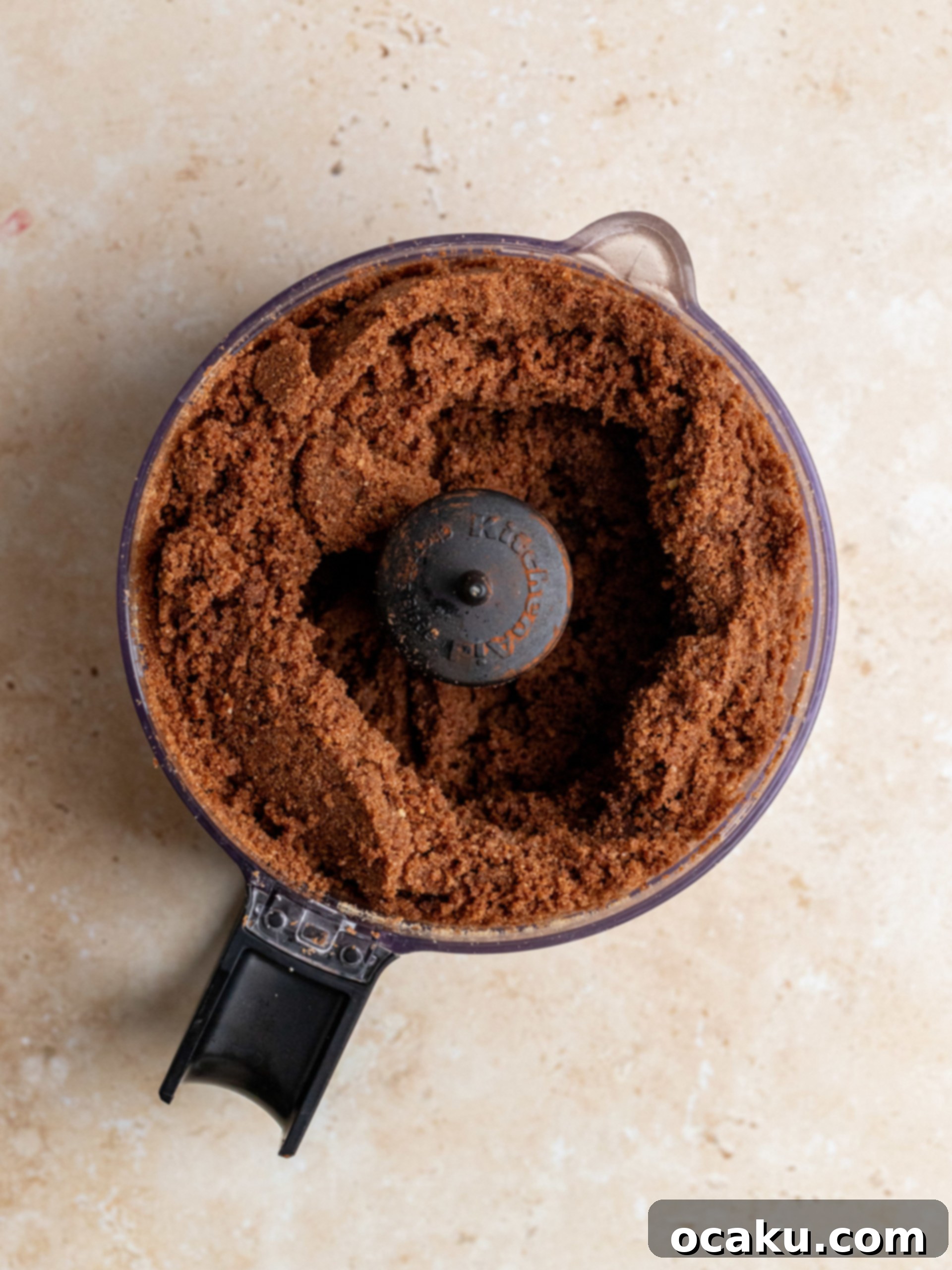 Crushed biscuits mixed with cocoa powder and butter, ready to form the cheesecake crust.