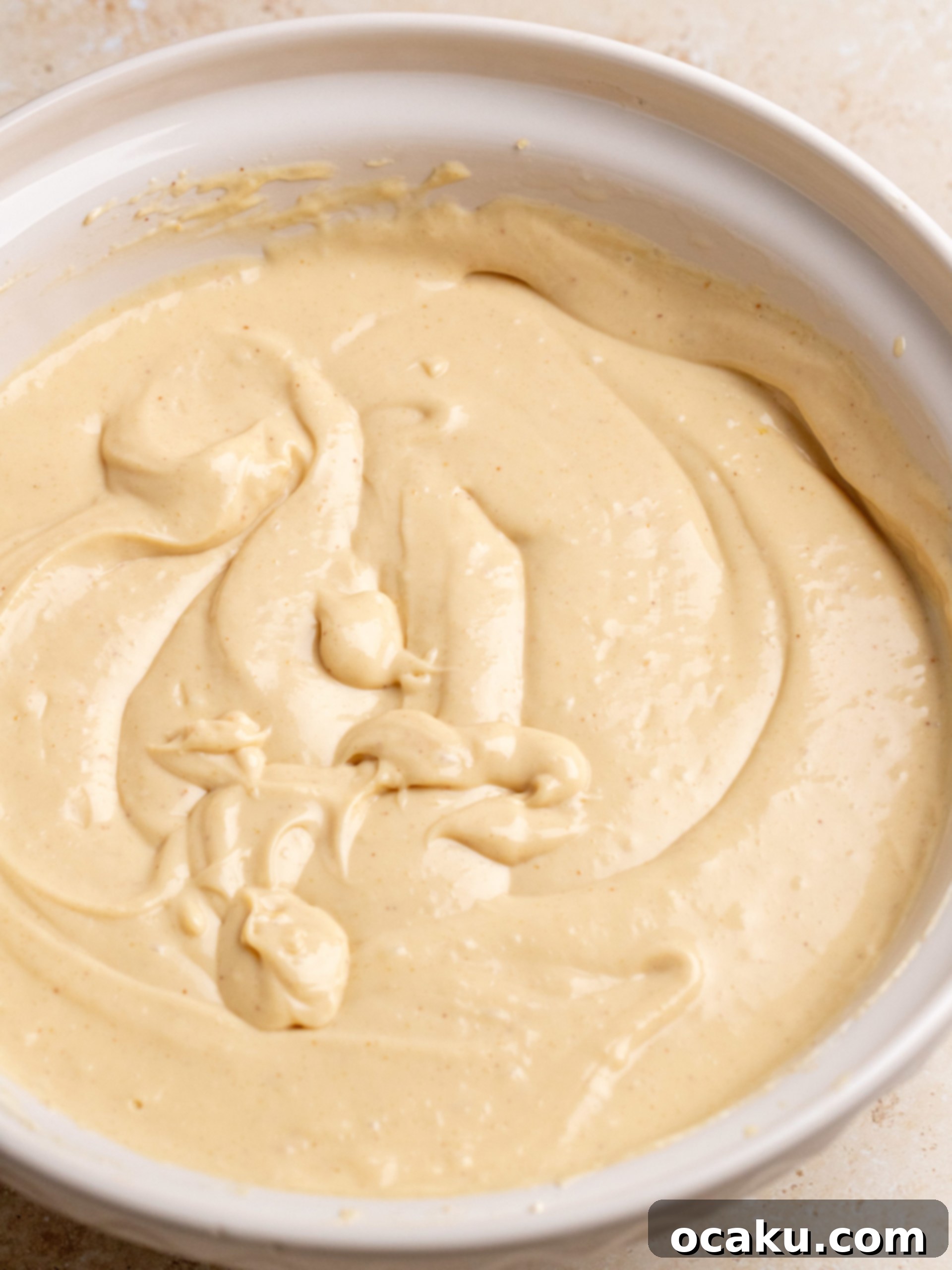 Pouring the smooth peanut butter cheesecake batter into the cooled cocoa crust in a springform pan.