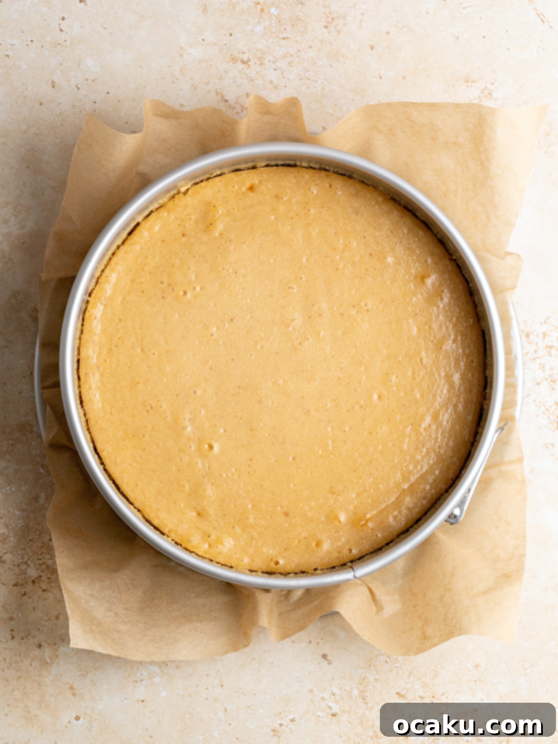 Smooth, glossy dark chocolate ganache being poured over the chilled peanut butter cheesecake.