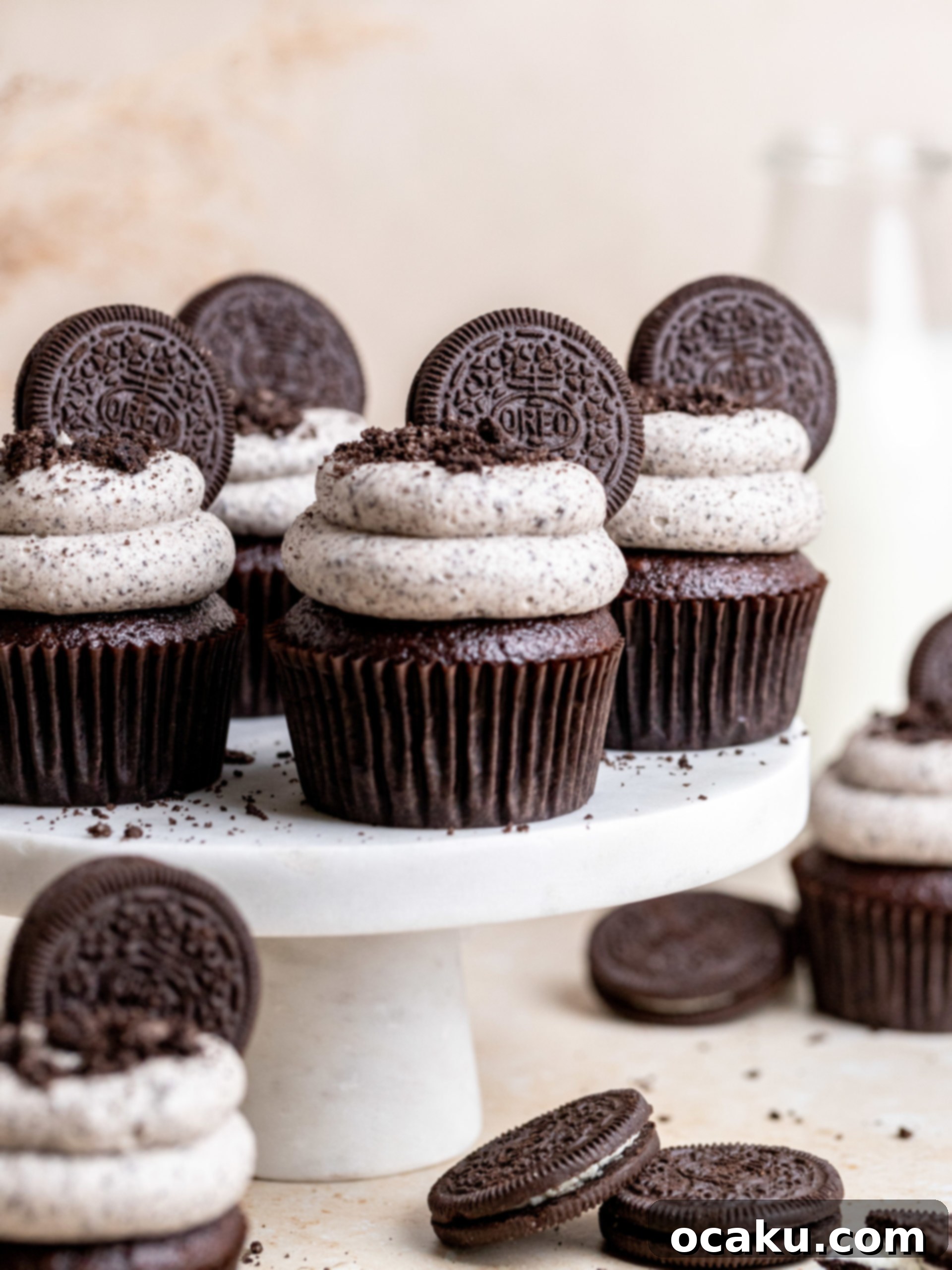 A perfectly frosted Oreo cupcake sits on a rustic wooden surface, highlighting its rich chocolate cake and creamy white Oreo buttercream, adorned with crushed Oreos and a full Oreo cookie.