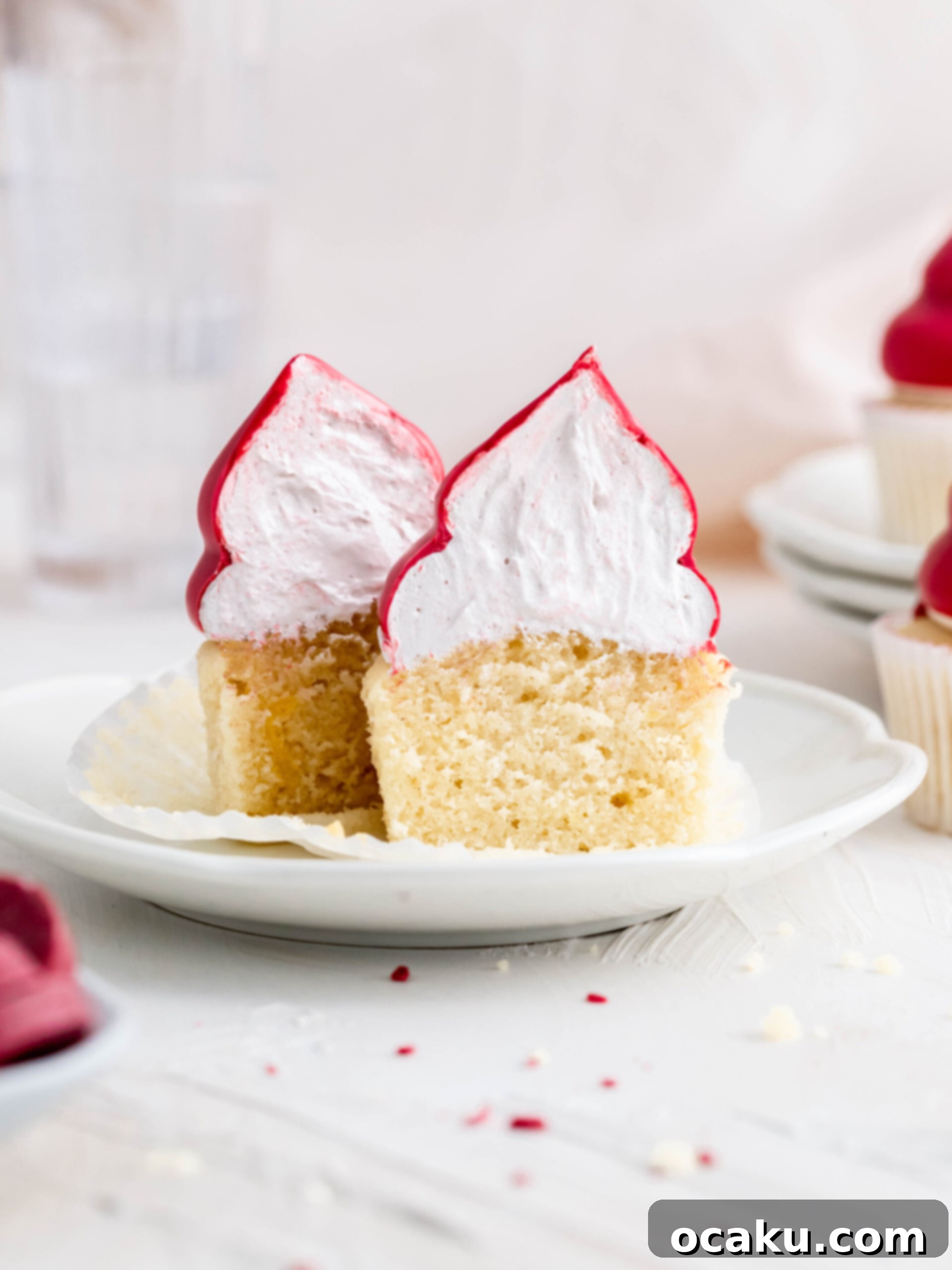 A Raspberry Cream Puff Cupcake cut in half, revealing its layers of almond cake and raspberry marshmallow fluff.