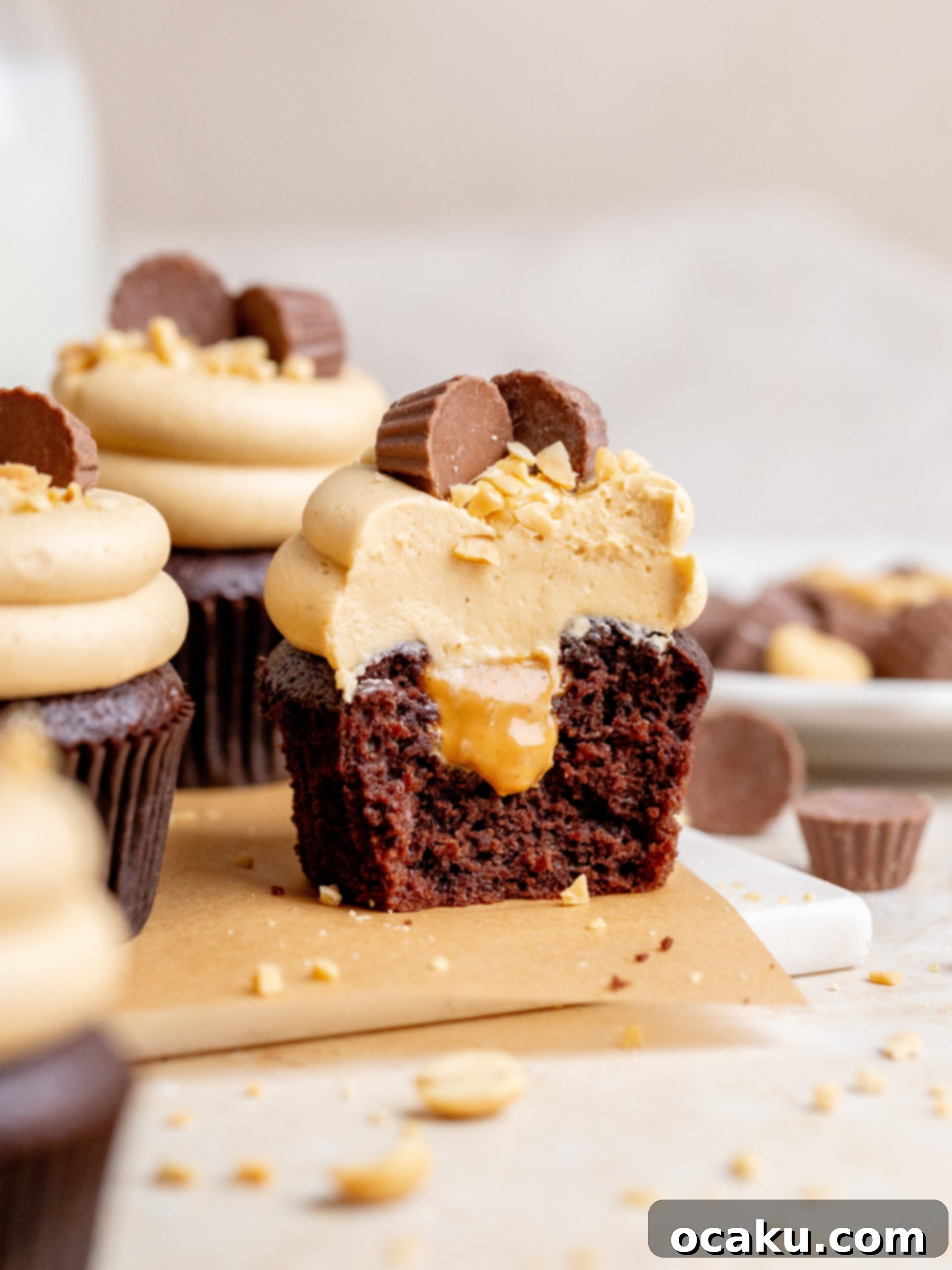 A beautifully frosted Peanut Butter Chocolate Cupcake topped with a mini Reese's peanut butter cup and chopped peanuts, showcasing its rich texture and decadent appeal.