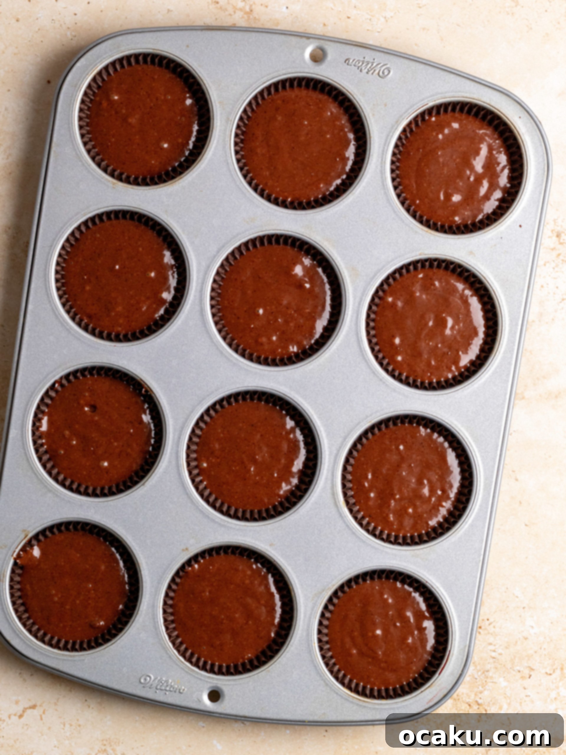 Chocolate cupcake batter poured into paper liners, ready for baking.