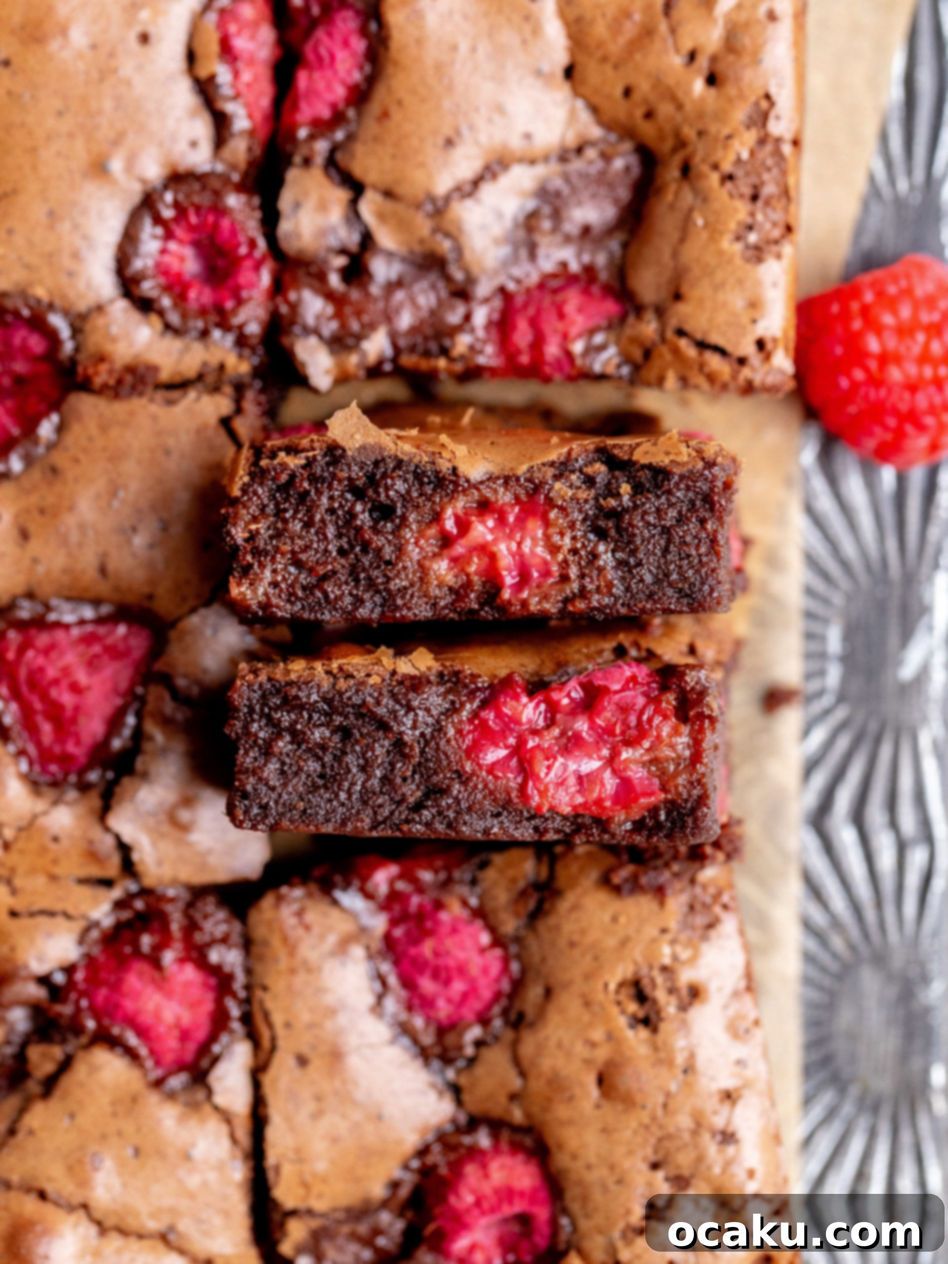 Stack of rich, dark raspberry brownies on a white plate, with a single raspberry on top.