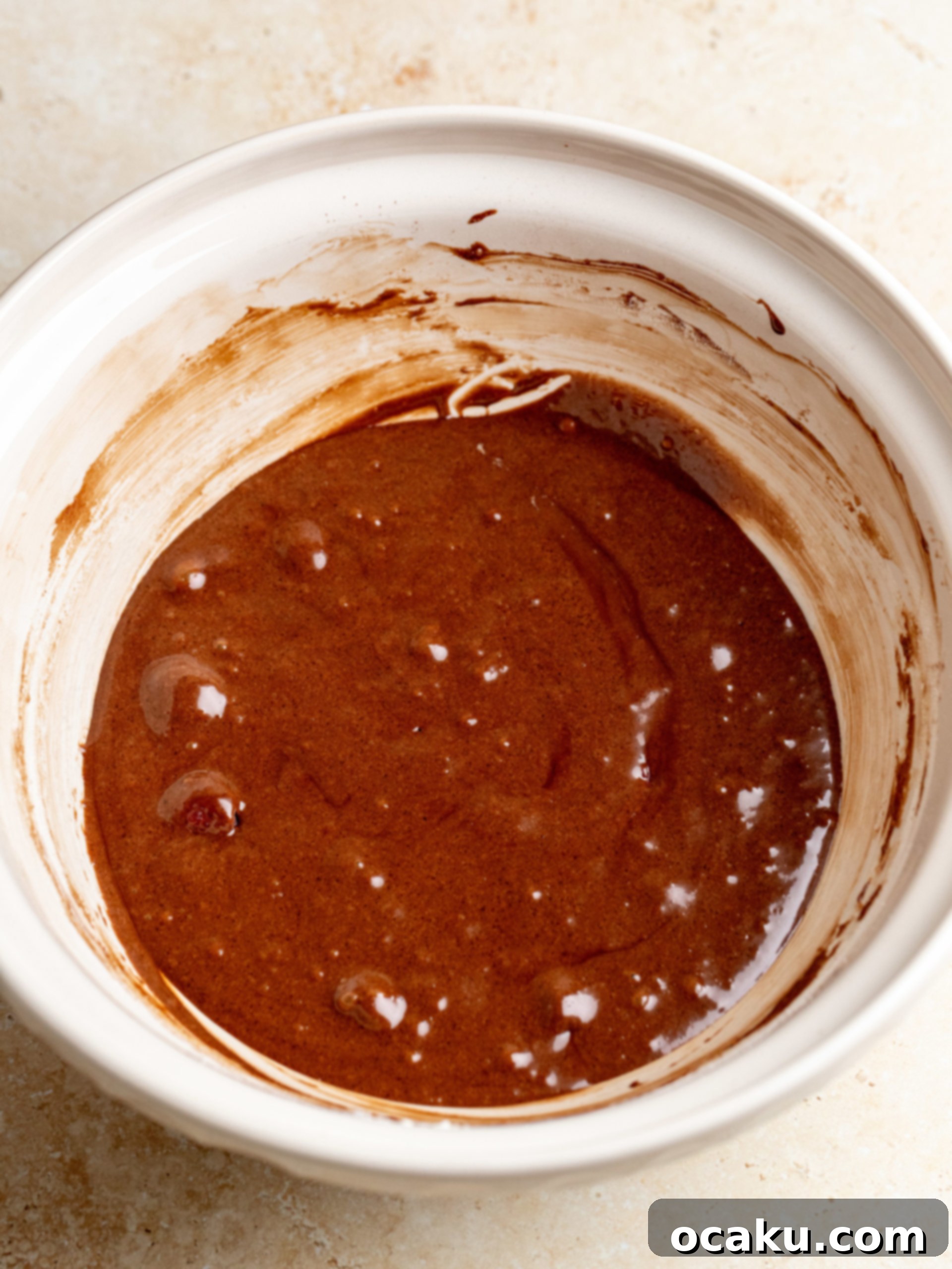 Melted butter and chocolate in a bowl, with cocoa powder ready to be mixed.